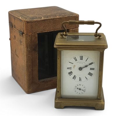 a small clock sitting next to a box on a white surface