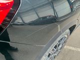 a black car parked in a parking lot with a reflection of a person in the rear window