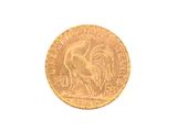 a gold coin with a rooster on it on a white surface