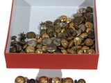 une boîte rouge remplie d'une multitude de boutons en or et en argent