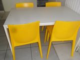 a white table with four yellow chairs around it