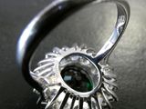 a close up of a silver ring with a green stone in it