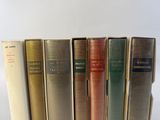 several books are lined up in a row on a white surface