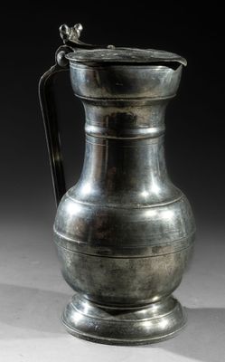 an old silver pitcher sitting on top of a white table