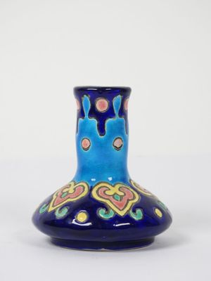 un vase bleu avec un motif sur une surface blanche