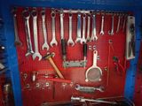 a red pegboard with a bunch of tools hanging on it