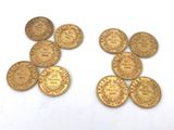 several gold coins sitting on top of each other on a white surface