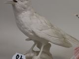 two figurines of birds that are sitting on a table
