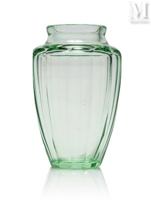 un vase en verre vert posé sur une surface blanche