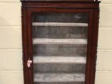 une vieille vitrine en bois avec des portes vitrées, posée sur le trottoir