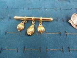 a gold pin with three bells on it next to a coin