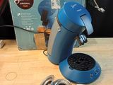 une cafetière bleue posée sur une table à côté d'une boîte de café