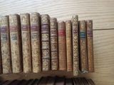 several old books are lined up on a shelf on a wooden table