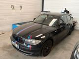 une voiture noire ornée d'une bande bleue et rouge, garée dans un garage