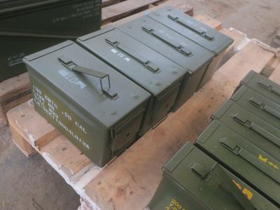 trois cartons verts posés sur une palette, elle-même posée sur une autre palette