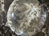 une plaque de verre portant un monogramme, posée sur une table