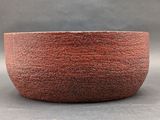 a close up of a red bowl on a gray surface