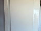 a white refrigerator in the corner of a room next to a window