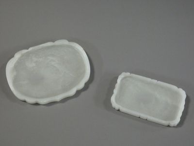 two white dishes on a table with a gray background