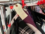 a lot of clothes hanging on a rack with a price tag