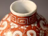 a red vase with white designs on it sitting on a table