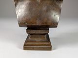 statue of a bust of a man on a pedestal on a white surface
