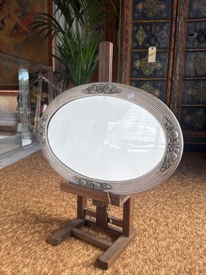 a large oval mirror on a stand in the middle of a room