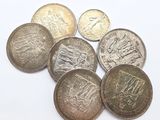 six different british coins sitting on top of each other on a white surface