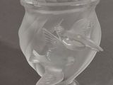 a glass vase with a bird on it on a table
