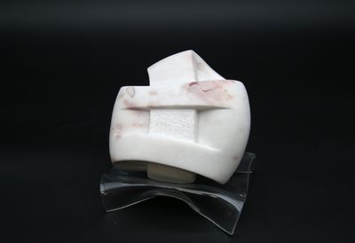 a white marble object with a cross on it on a black surface