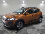La voiture orange est garée sur un sol en carrelage à damier.