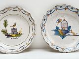 deux assiettes avec des oiseaux et une cage à oiseaux