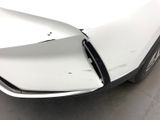 the front end of a white car with a dented bumper