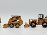 five toy construction vehicles that are lined up on a white surface