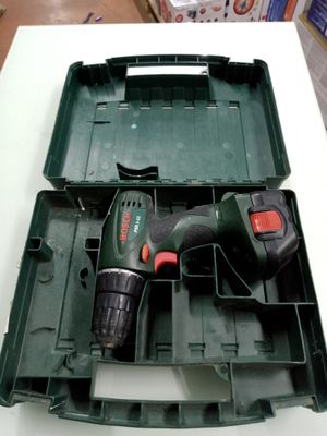 une perceuse sans fil dans un coffret en plastique posé sur une table