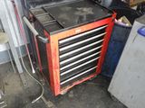 une armoire à outils rouge comportant de nombreux tiroirs, dans un garage
