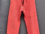 un vieux pantalon rouge suspendu à un porte-vêtements
