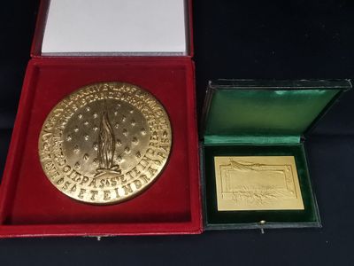 l'image d'une médaille d'or dans un coffret rouge posé sur un fond noir