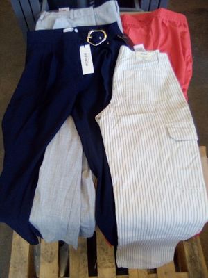 trois paires de pantalons posées sur une palette dans un magasin