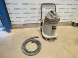 une photo d'un aspirateur posé sur le sol, à côté d'un tuyau