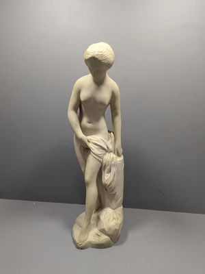 une statue en marbre blanc représentant une femme tenant un sac