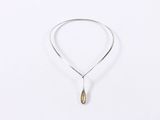 a silver necklace with a tear shaped pendant hanging from it ' s side