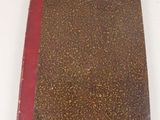 un livre marron et rouge posé sur une table blanche