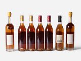 six bottles of wine are lined up in a row on a white surface
