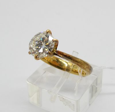 une bague de fiançailles en or sertie d'un diamant posé sur un bloc d'acrylique transparent