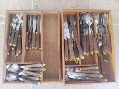 two wooden trays with silverware in them on a tile floor