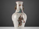 un vase blanc avec un tableau posé sur une table