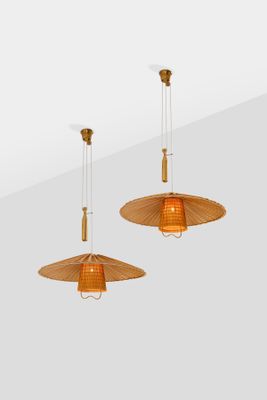 two hanging lamps made of rattan wood and glass on a white wall