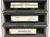 trois wagons de train miniature sont empilés dans une boîte posée sur une surface blanche
