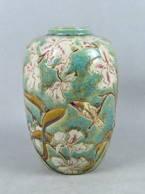un vase vert orné d'oiseaux et de fleurs